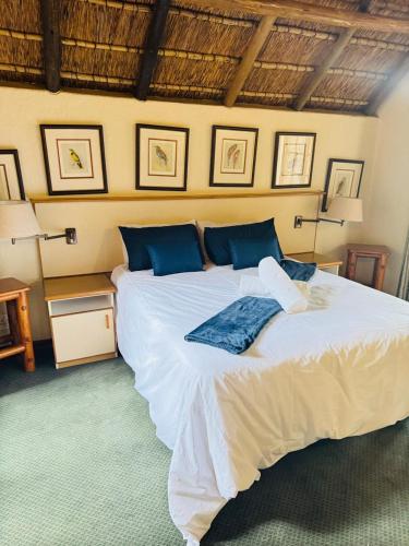 a bedroom with a large white bed with blue pillows at Mabalingwe Mistykie Lodge in Warmbaths