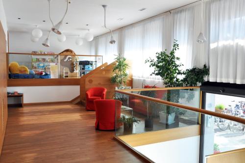 a living room with a staircase and red chairs at Lacroma Bio Hotel & Apartments in Grado