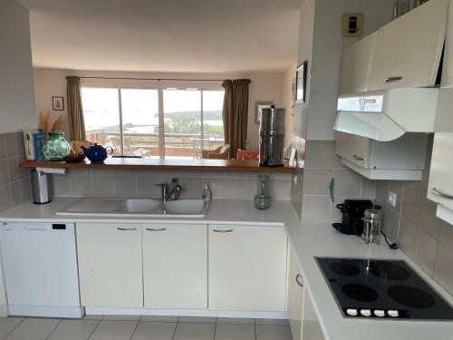 une cuisine avec des armoires blanches, un évier et une fenêtre dans l'établissement Bonifacio accès mer et golf - vue exceptionnelle, à Bonifacio