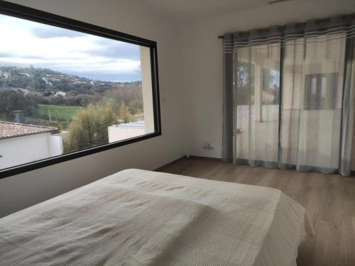 a bedroom with a large window and a large bed at Haut de Villa avec piscine in Bastelicaccia