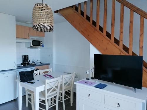 Il comprend une cuisine avec une table blanche et une télévision. dans l'établissement Duplex résidence la cascade, à Dolus-d'Oléron