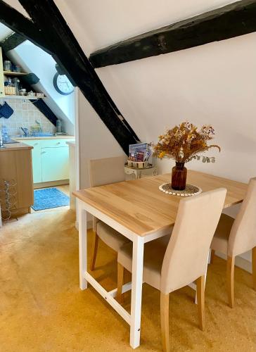 une table à manger avec des chaises blanches et un vase avec une plante dans l'établissement Le Cocon - La Vue des Remparts- Historical center, à Dinan