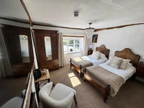 a bedroom with two beds and a chair at The Bowl Inn in Charing