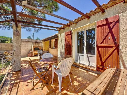 une terrasse avec une table et des chaises ainsi qu'une porte de grange dans l'établissement Maison avec jardin sur marseillan, à Marseillan