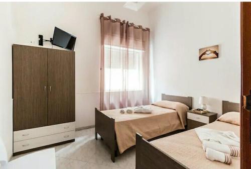 a bedroom with two beds and a cabinet and a television at Villa Anny Fronte Mare in Avola