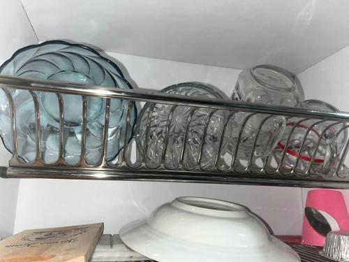 ein Regal voller Glasgeschirr und einer Vase in der Unterkunft Nita's Sweet Apartment Gunawangsa Manyar 2BR - close to Unair Galaxy Mall in Surabaya