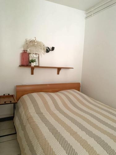 - une chambre avec un lit et une étagère sur le mur dans l'établissement Le Petit Provençal, à Béziers