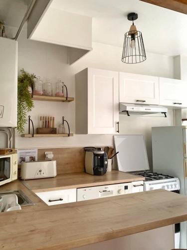 une cuisine avec des armoires blanches et un comptoir dans l'établissement Le Petit Provençal, à Béziers