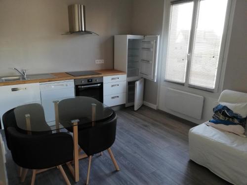 une cuisine avec une table et des chaises dans une pièce dans l'établissement F1 Meublé neuf prox autoroute et gare, à Saint-Étienne