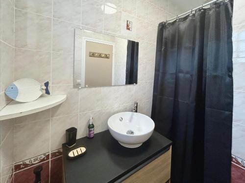 La salle de bains est pourvue d'un rideau de douche noir et d'un lavabo. dans l'établissement Maisonnette pour 2 personnes à 50m de la plage, à Saint-Palais-sur-Mer