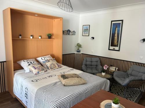 une chambre avec un grand lit et deux chaises dans l'établissement Maisonnette pour 2 personnes à 50m de la plage, à Saint-Palais-sur-Mer