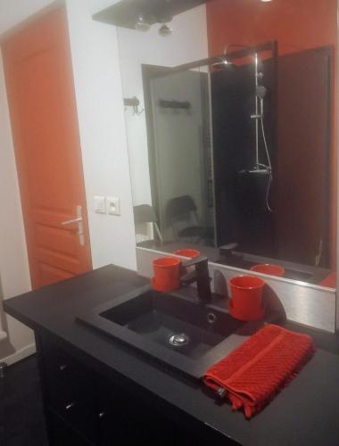 une salle de bain avec un lavabo avec des tasses rouges dessus dans l'établissement COSY ZEN HYPER CENTRE APARTMENT***, à Rochefort