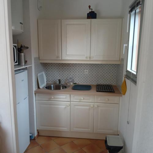 une cuisine avec des armoires blanches et un évier dans l'établissement Fregate, à Saint-Mandrier-sur-Mer