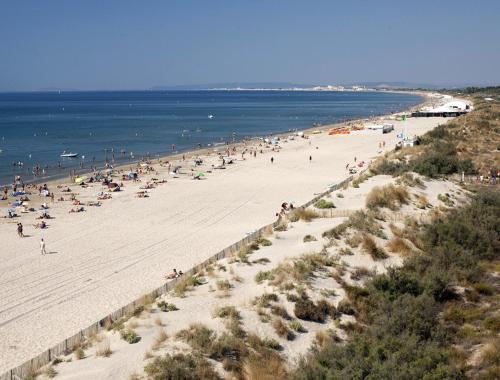 un grupo de personas en una playa cerca del océano en Vittoria Immobilier 1- Vue dégagée - Terrasse - Chèques Vacances acceptés, en La Grande-Motte