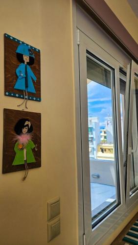a wall with two pictures and a window at Rooftop flat in Chalkida