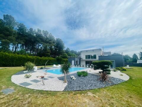 une cour arrière avec une piscine et une maison dans l'établissement Villa Californie avec piscine près du circuit des 24H, à Changé