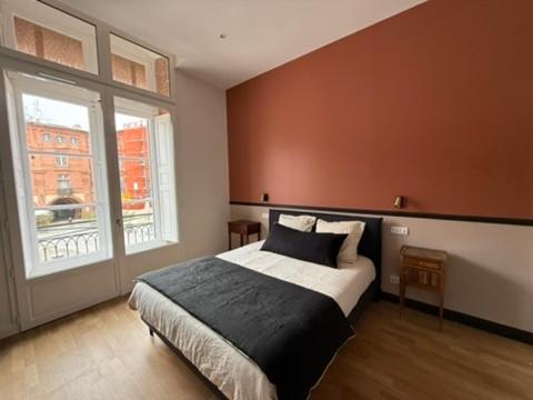 une chambre avec un lit et une grande fenêtre dans l'établissement La réserve des drapiers, à Montauban