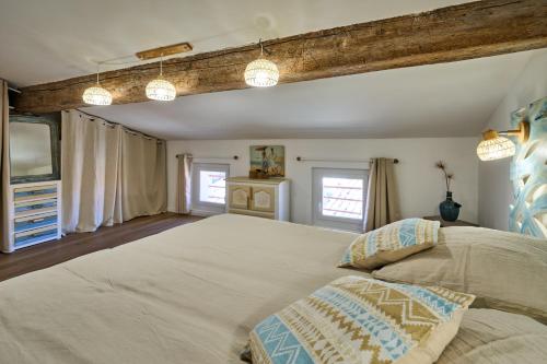 a bedroom with a large bed and two windows at Charme, confort en centre-ville in Limoux