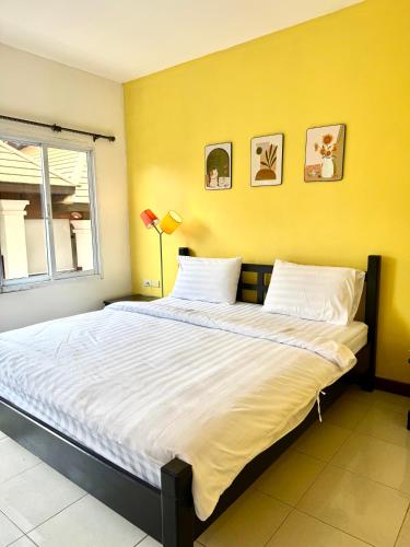 a large bed in a room with a yellow wall at KK Hotel in Pakse