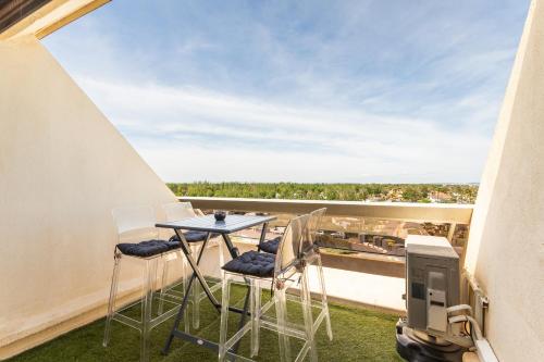d'un balcon avec une table et des chaises, ainsi que d'une télévision. dans l'établissement Village Naturiste - Hélio L vue mer, au Cap d'Agde