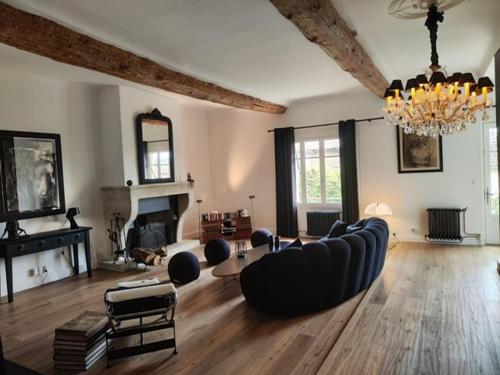 a living room with a couch and a chandelier at Bastide du château in Montfaucon