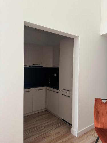 a kitchen with white cabinets and a white wall at AboutArtApartments - By the river in Wrocław