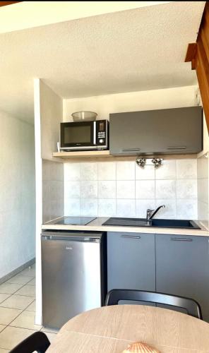une cuisine avec un évier et un micro-ondes dans l'établissement Studio rive droite, à Palavas-les-Flots