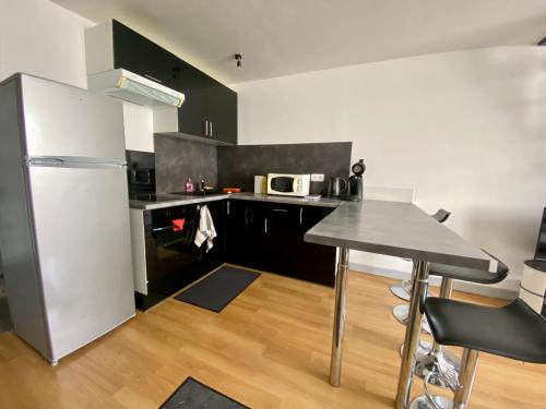 une cuisine avec un réfrigérateur en acier inoxydable et une table dans l'établissement Appartement mezzanine au calme, à La Rochelle