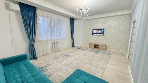a living room with a blue couch and a television at #52 Просторная 3 комнатная квартира in Atyraū