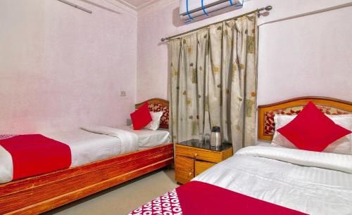a bedroom with two beds with red and white pillows at Hotel O Embassy in Bodh Gaya