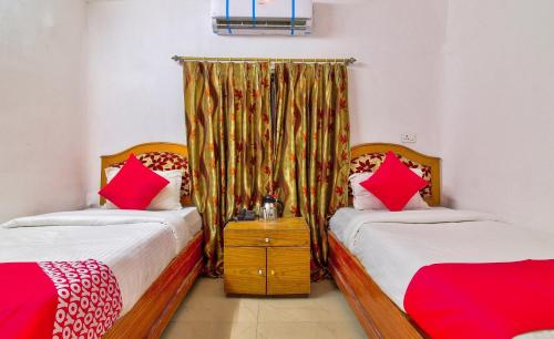 a bedroom with two beds with red pillows at Hotel O Embassy in Bodh Gaya
