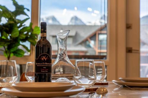 a bottle of wine sitting on a table with glasses at Modern Mountain Oasis Top floor 2 level 2bd in Canmore