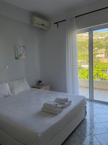 a white bedroom with a bed with towels on it at Marina Apartaments in Himare