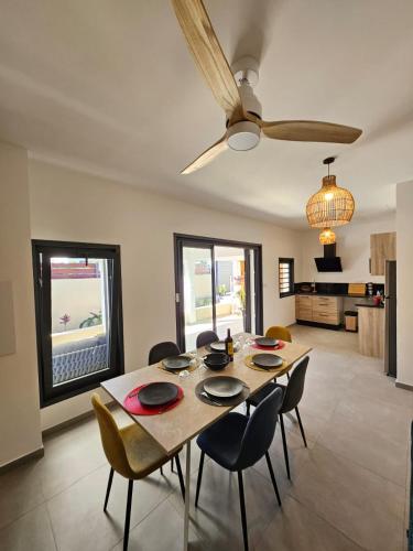 a dining room table with chairs and a ceiling fan at joly brise in Saint-Pierre