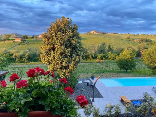 a garden with red flowers and a swimming pool at Sorriso Dei Maestri in Calosso