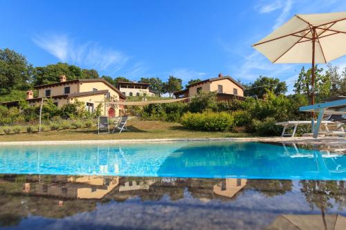 una piscina con ombrellone e una casa di Poggio La Croce a Scarlino