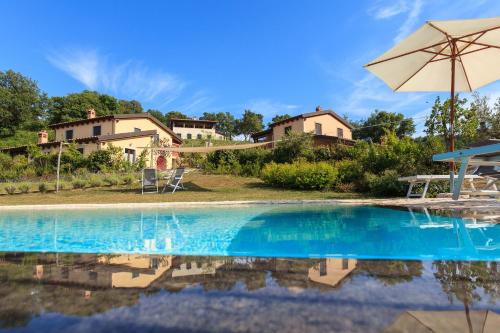 a swimming pool with an umbrella and a house at Poggio La Croce in Scarlino