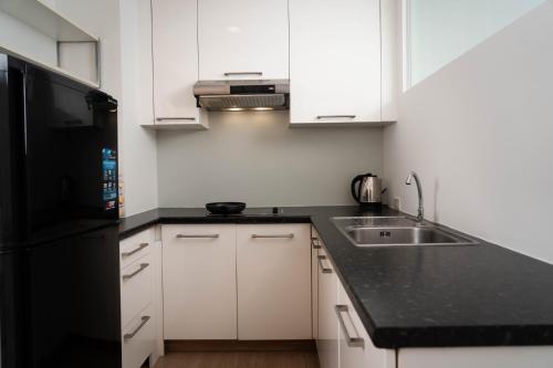 a kitchen with white cabinets and a black refrigerator at Baan K Residence in Bangkok