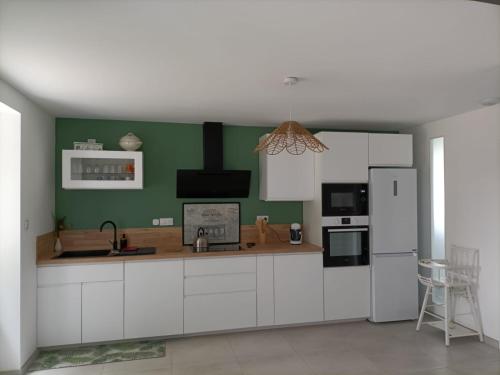 - une cuisine avec des placards blancs et un mur vert dans l'établissement Maison familiale à la campagne, à Cassagne