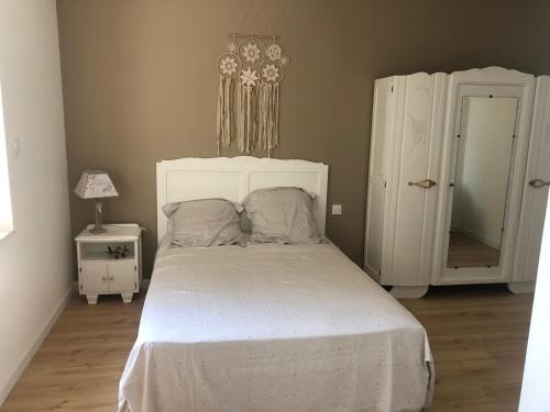 - une chambre avec un lit blanc et une tête de lit blanche dans l'établissement Maison familiale à la campagne, à Cassagne