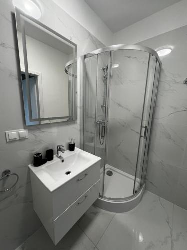 a white bathroom with a shower and a sink at AboutArtApartments - By the river in Wrocław