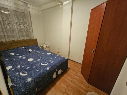 a small bedroom with a bed and a wooden door at Apartman K&M in Vranje