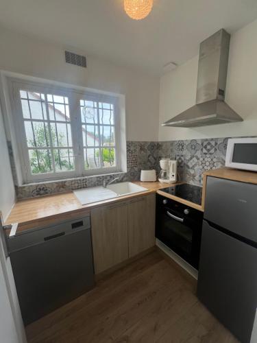 メルリモン・プラージュにあるLes Sylphides - Villa de charme à Merlimont-Plage - 4 personnesのシンクとコンロと窓のあるキッチン