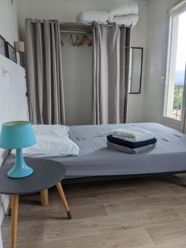un lit dans une chambre avec une lampe bleue et une table dans l'établissement Agréable appartement à 3min à pied de la plage, à Argelès-sur-Mer