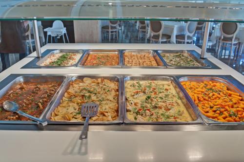 a buffet filled with different types of food in trays at Palmariva Beach Hotel in Eretria