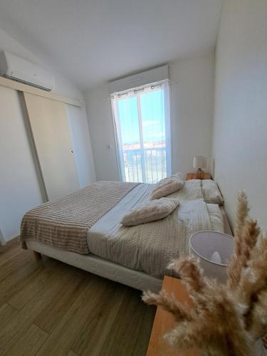 une chambre avec un grand lit et une fenêtre dans l'établissement Appartement proche bord de mer, au Barcarès