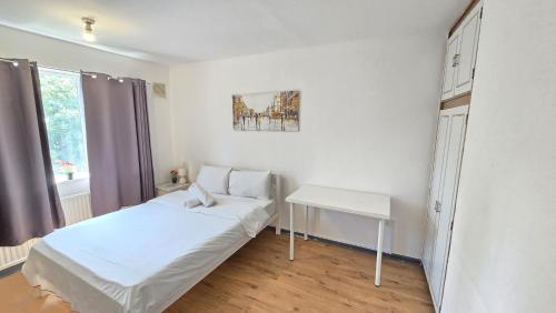 a white bedroom with a bed and a table at Canary wharf cottage in London