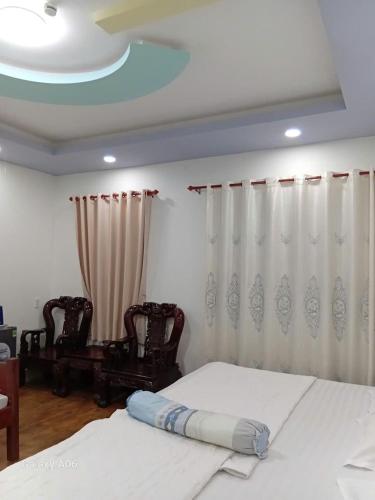 a bedroom with a bed and two chairs at HOTEL MOTeL ĐỒNG KHỞI in Ben Tre