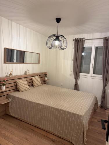 une chambre avec un grand lit et un lustre dans l'établissement Appartement 50m2, résidence privée avec piscine, tennis et à 100 m de la plage, au Lavandou