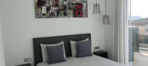 ein Schlafzimmer mit einem Bett mit zwei Kissen und einem Gemälde in der Unterkunft Casa Mariposa, 3 bedroom villa in Benijofar in Benijófar
